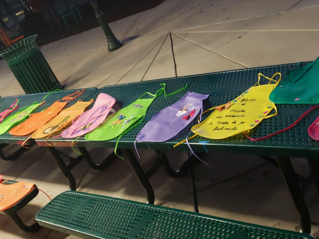 Decorated mandilitos (little aprons) laid out side by side on top of a park bench.